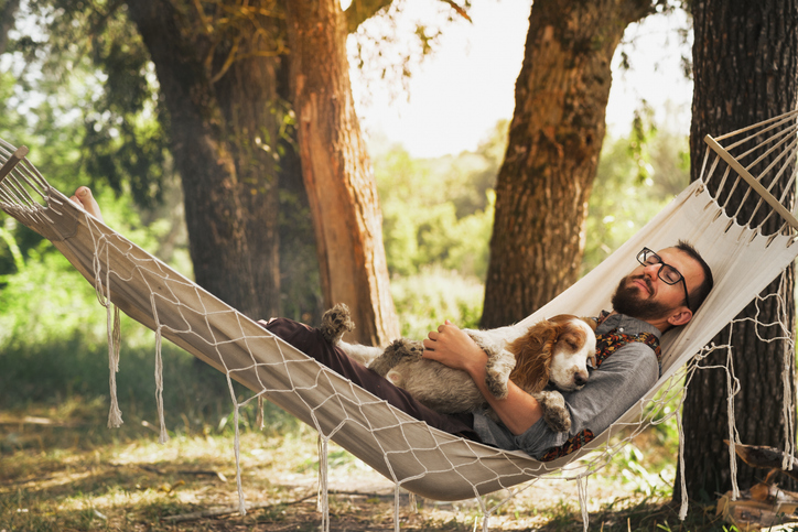Man relaxing in hammock with dog, representing peace of mind and security